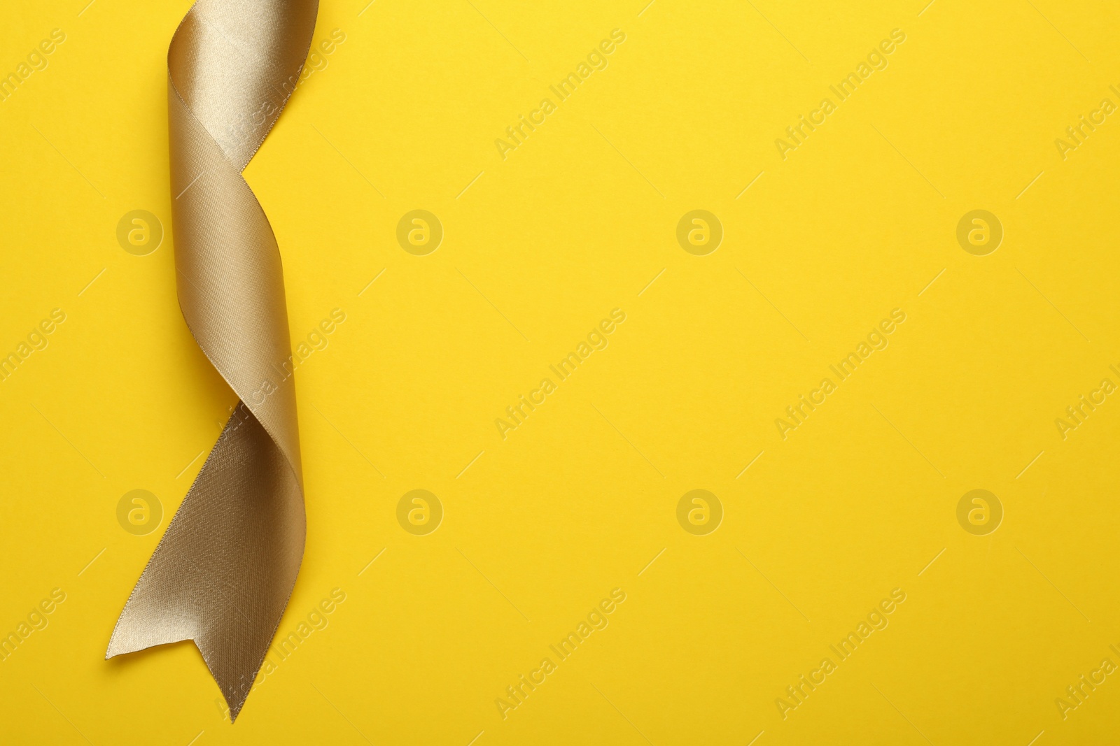 Photo of Beautiful ribbon on yellow background, top view. Space for text