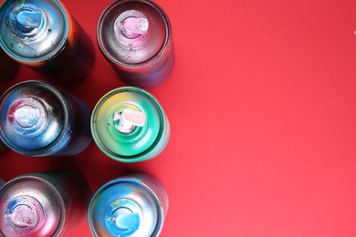 Photo of Many spray paint cans on red background, flat lay. Space for text