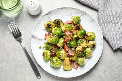 Delicious fried Brussels sprouts with bacon served on grey table, flat lay