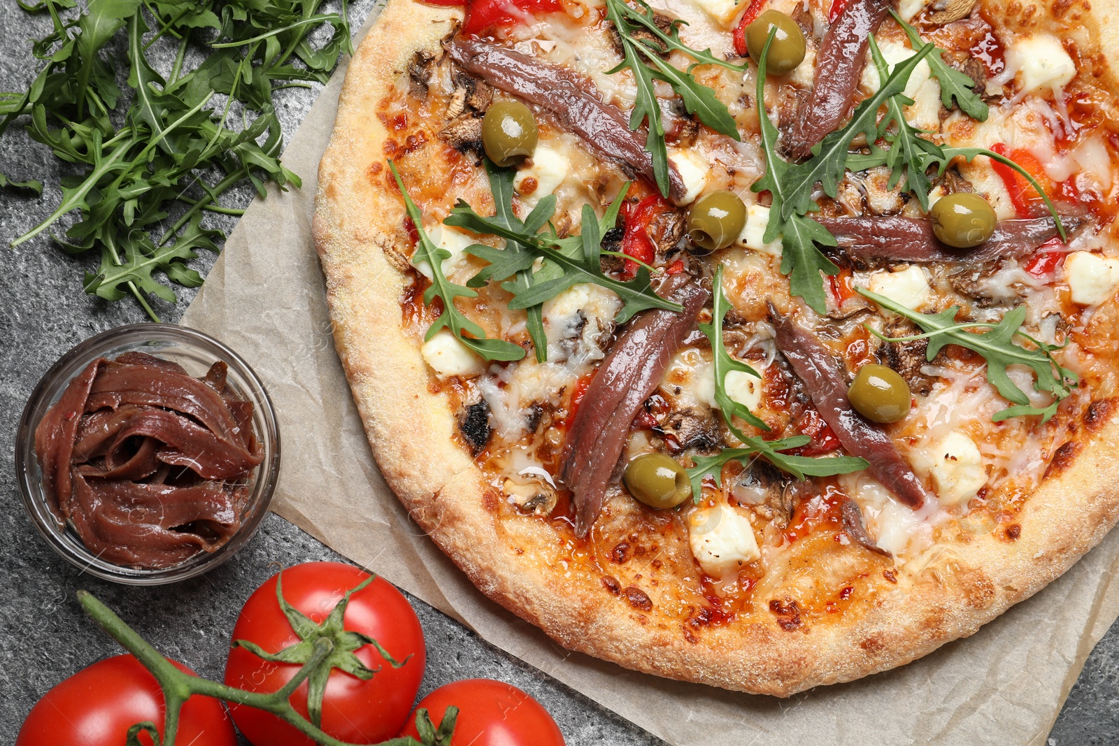 Photo of Tasty pizza with anchovies and ingredients on grey table, flat lay