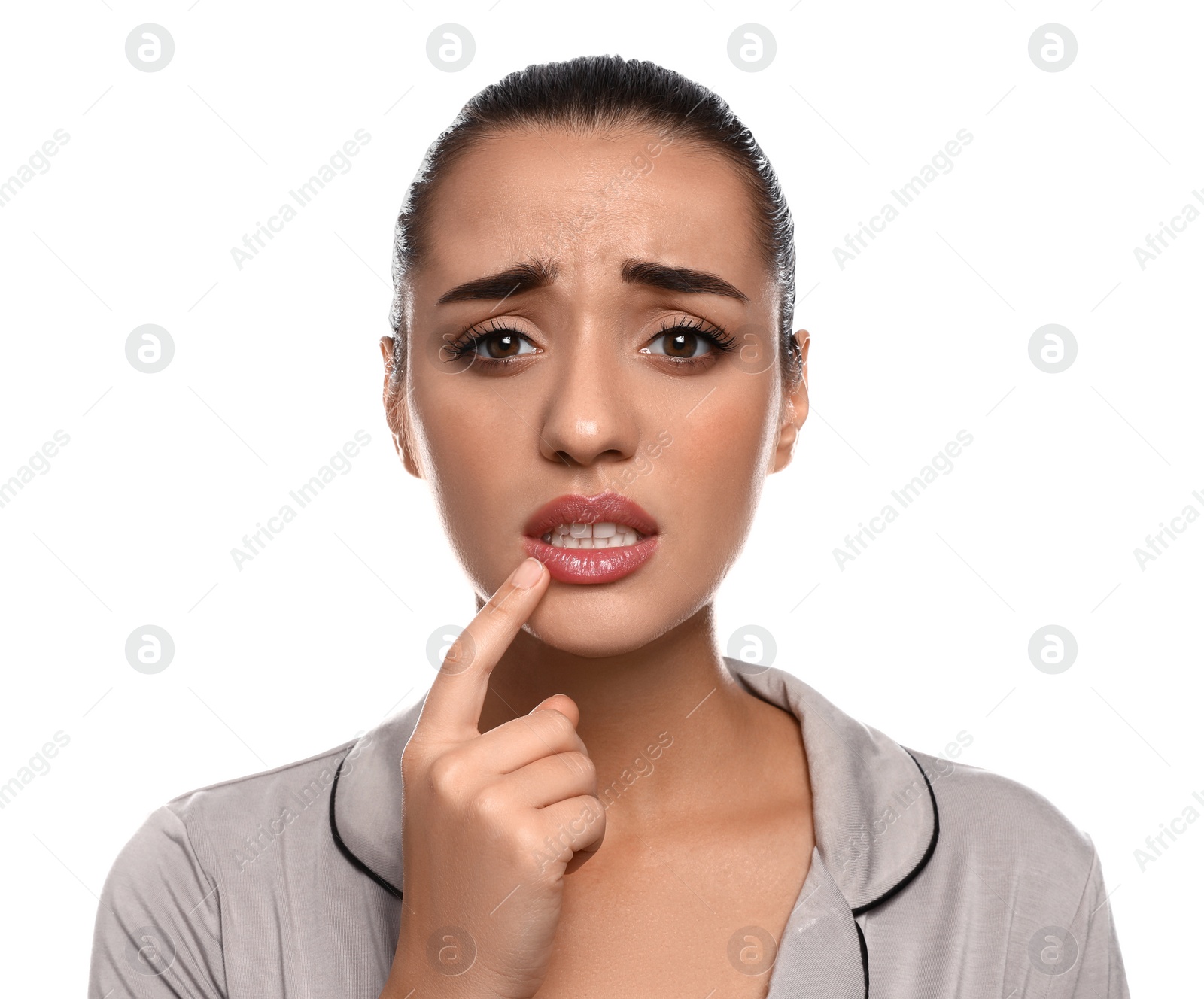 Photo of Emotional woman with herpes touching lips on white background