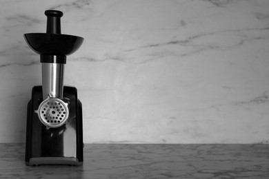 Photo of Modern electric meat grinder on marble table. Space for text
