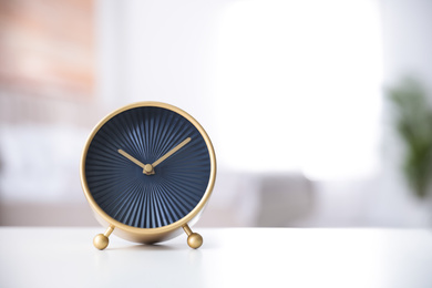 Photo of Stylish black clock on white table indoors. Space for text