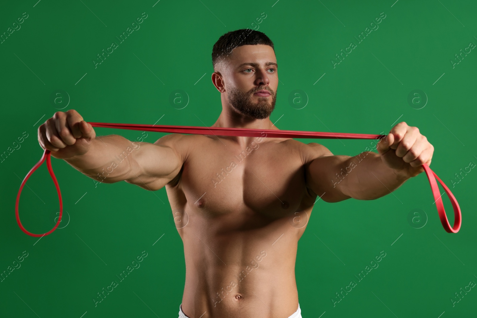 Photo of Muscular man exercising with elastic resistance band on green background