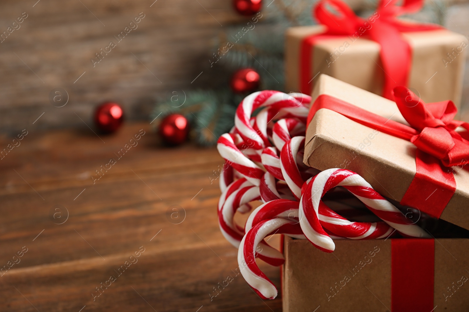 Photo of Candy canes in gift box on wooden table, space for text. Traditional Christmas treat