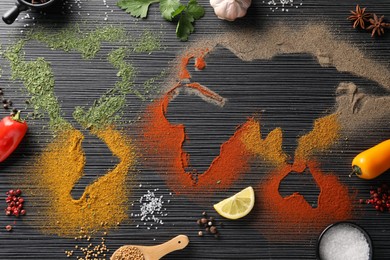 Photo of World map of different spices and products on black wooden table, flat lay