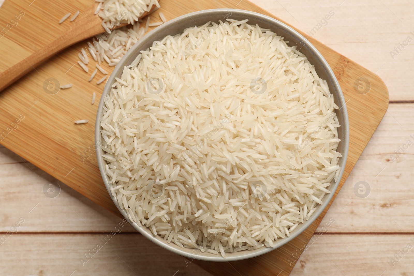 Photo of Raw basmati rice in bowl on white wooden table, top view