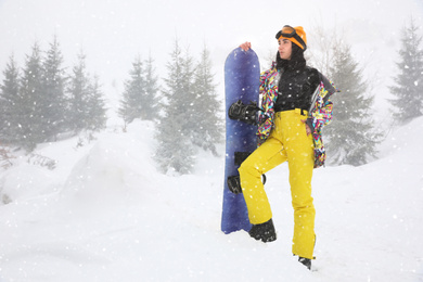 Young woman with snowboard wearing winter sport clothes outdoors