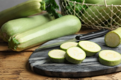 Photo of Sliced zucchini and grey marble board on wooden table, closeup
