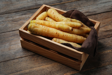 Photo of Raw white carrots in crate on wooden table