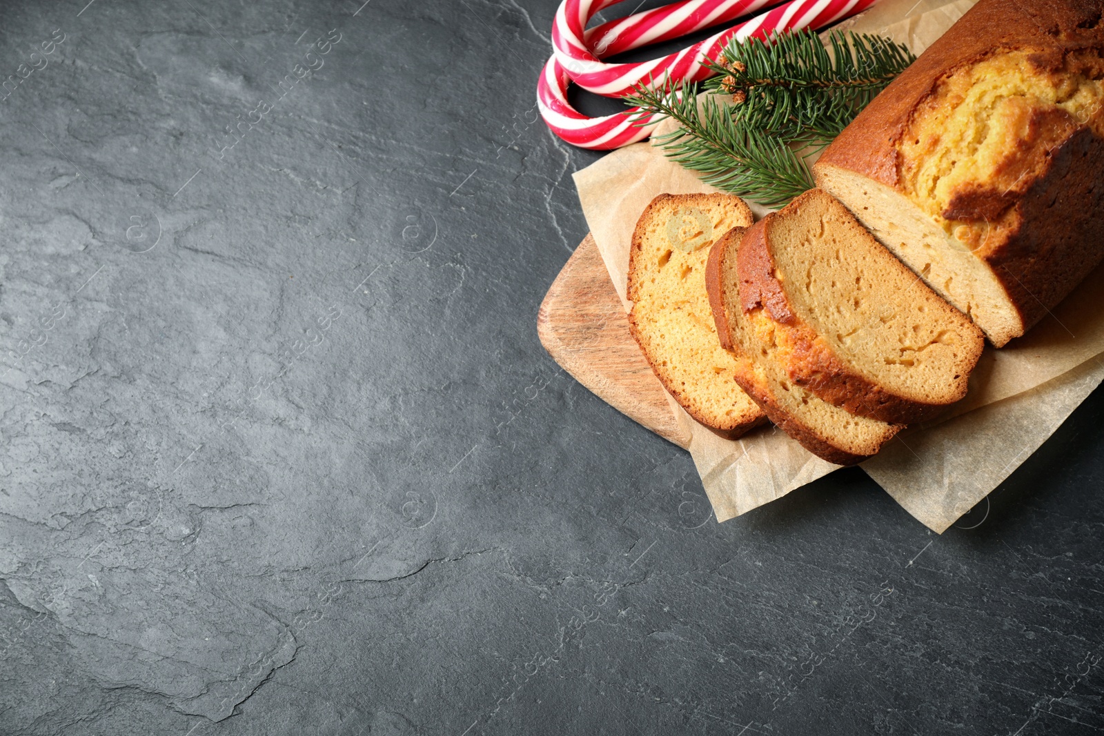 Photo of Delicious gingerbread cake, candy canes and fir branches on dark table, flat lay. Space for text