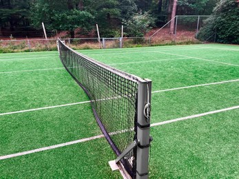 Tennis court with green grass and net outdoors