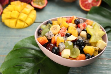 Delicious exotic fruit salad on light blue wooden table, closeup