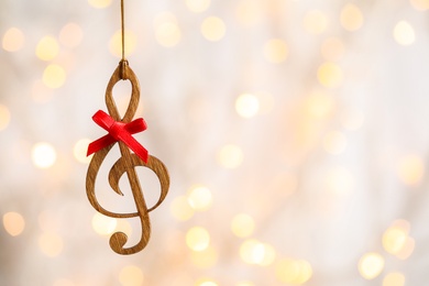 Photo of Wooden treble clef against blurred lights, space for text. Christmas music