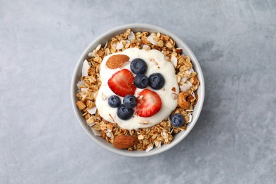 Photo of Tasty granola, yogurt and fresh berries in bowl on light grey table, top view. Healthy breakfast
