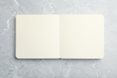 Photo of Stylish open notebook on marble table, top view. Space for design
