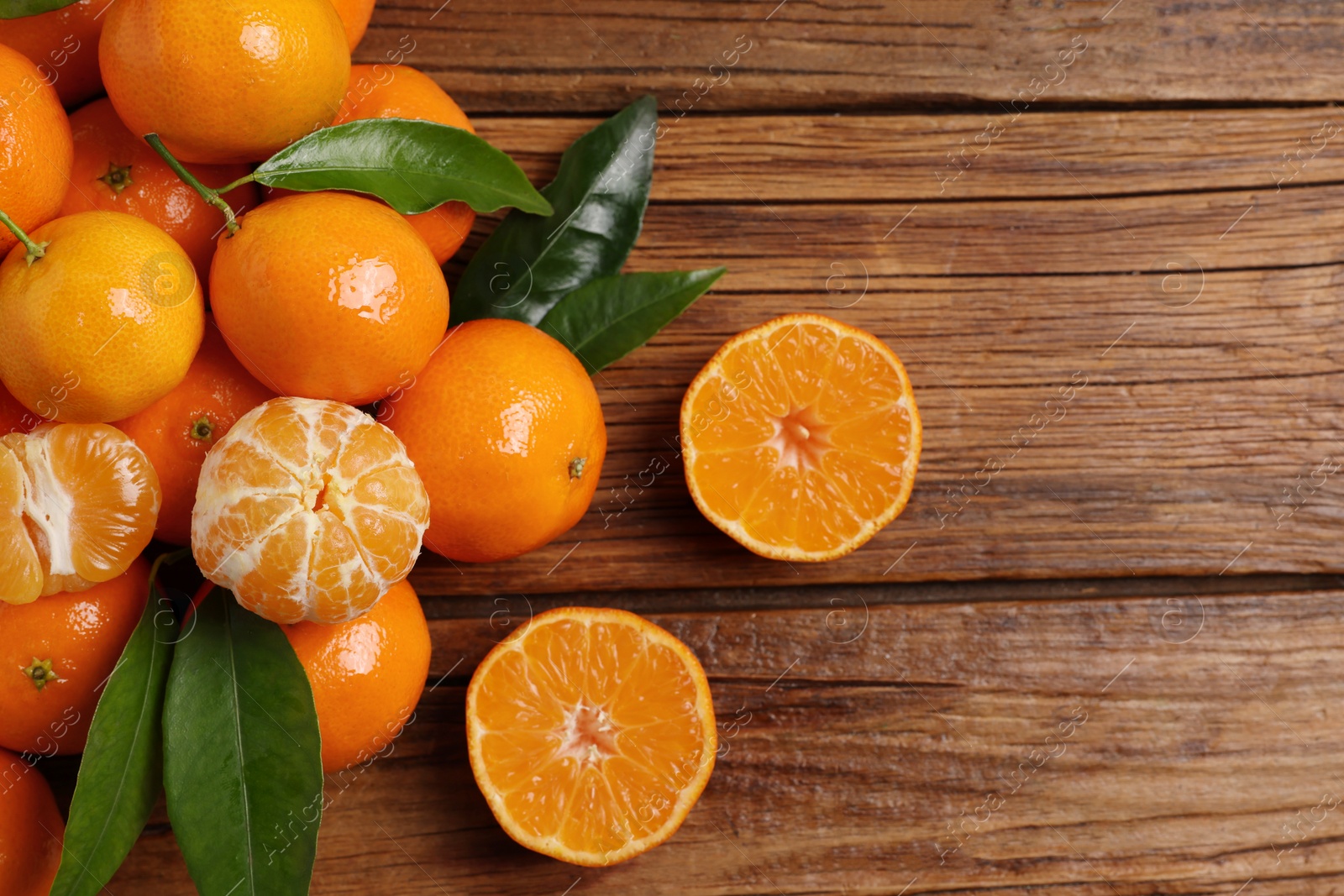 Photo of Fresh tangerines with green leaves on wooden table, top view. Space for text