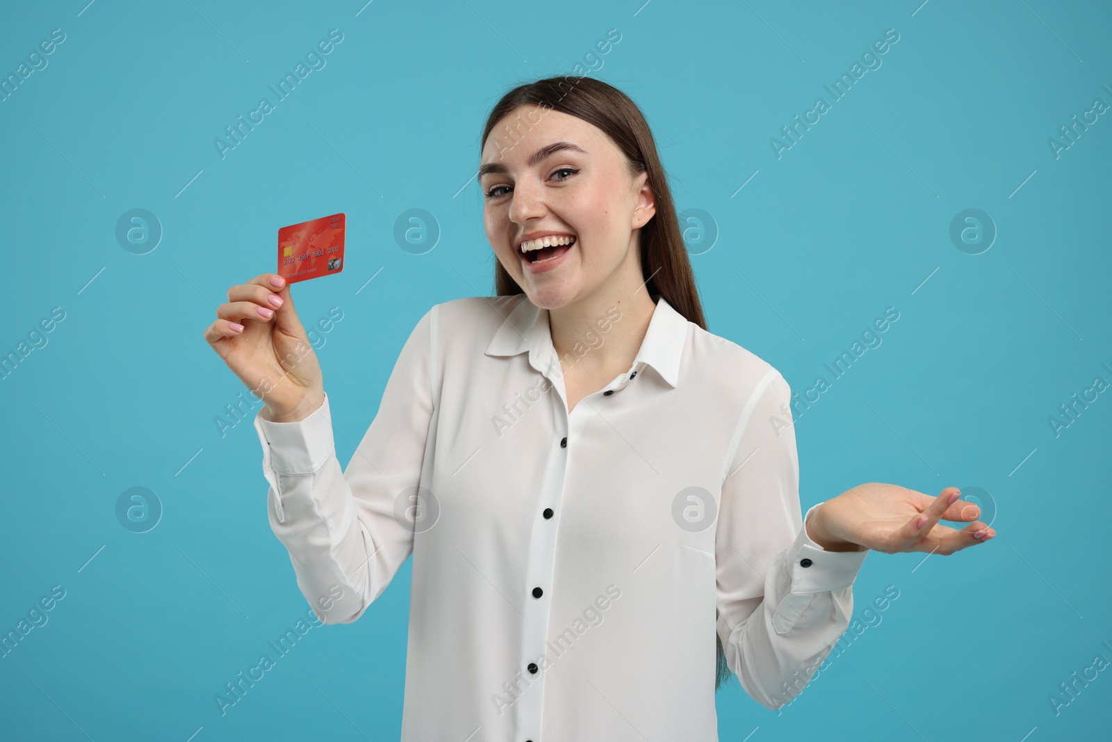 Photo of Happy woman with credit card on light blue background