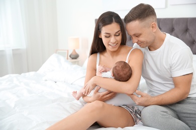 Photo of Happy couple with their newborn baby on bed. Space for text