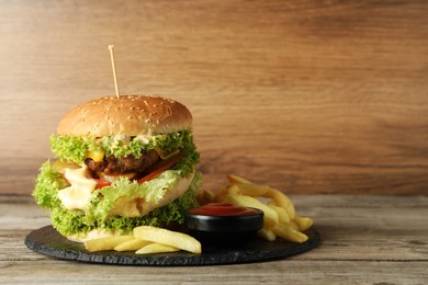 Photo of Burger with delicious patty, french fries and sauce on wooden table, space for text