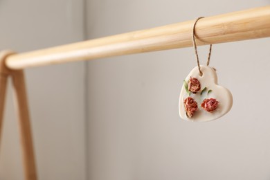 Photo of Wooden clothes rack with beautiful heart shaped scented sachet indoors