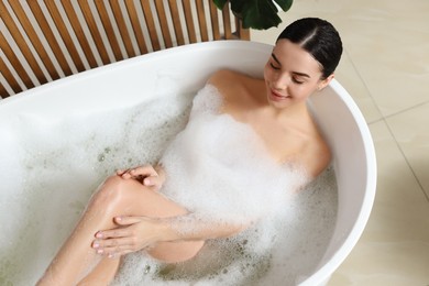 Beautiful young woman taking bubble bath at home