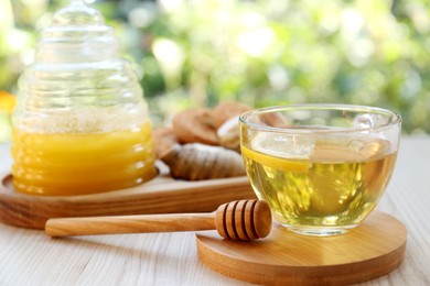 Photo of Cup of delicious tea with lemon, honey and ginger on wooden table outdoors