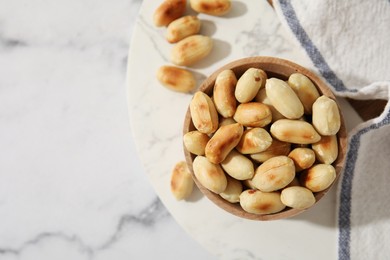 Roasted peanuts in bowl on white marble table, top view. Space for text