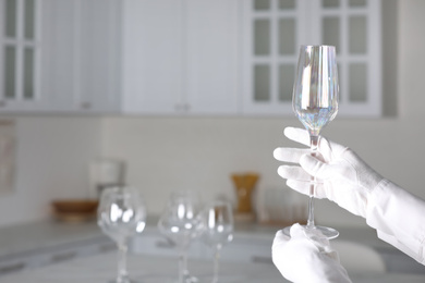 Photo of Person in white gloves checking cleanliness of glass indoors, closeup. Space for text