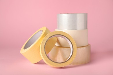 Photo of Many rolls of adhesive tape on pink background