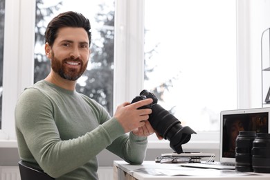 Photo of Professional photographer with digital camera at table in office