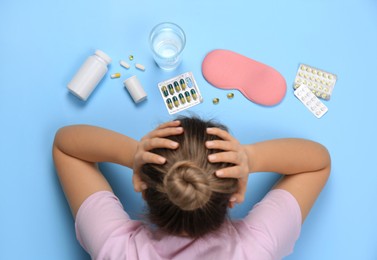 Woman surrounded by different pills on turquoise background, top view. Insomnia treatment