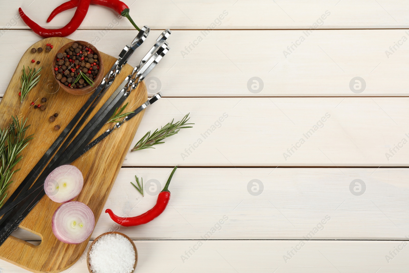 Photo of Flat lay composition with metal skewers on white wooden table. Space for text