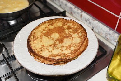 Photo of Plate of freshly made crepes on stove in kitchen