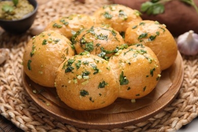 Photo of Traditional pampushka buns with garlic and herbs on plate, closeup