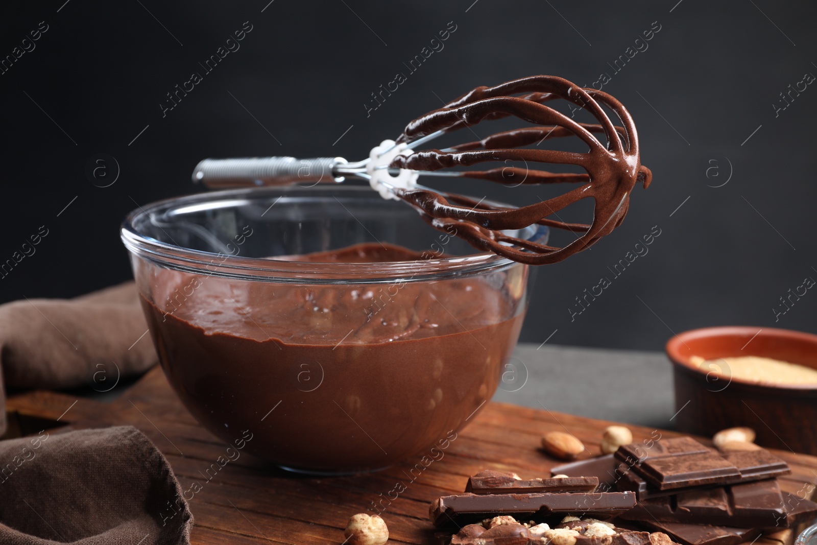 Photo of Bowl of chocolate cream, whisk and ingredients on table, closeup