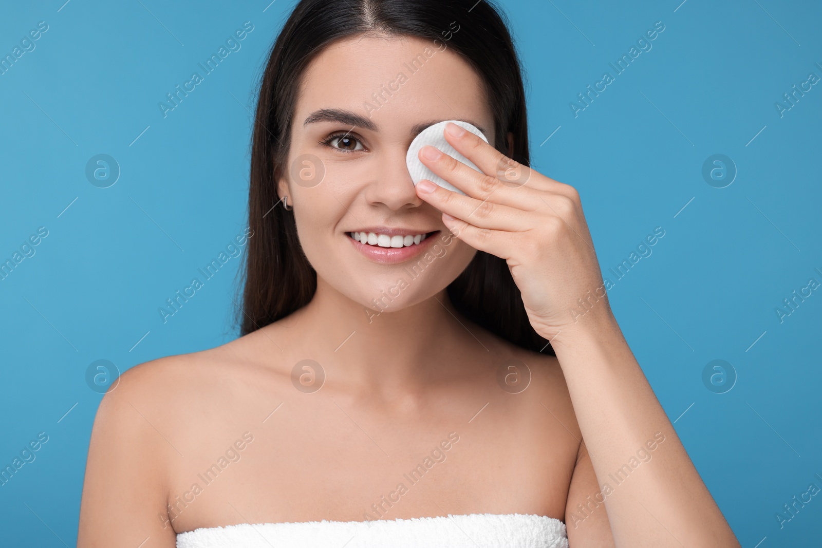 Photo of Young woman with cotton pad on light blue background