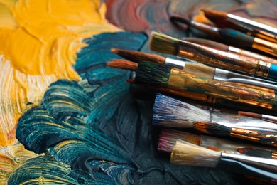 Photo of Different paint brushes on canvas, closeup. Space for text