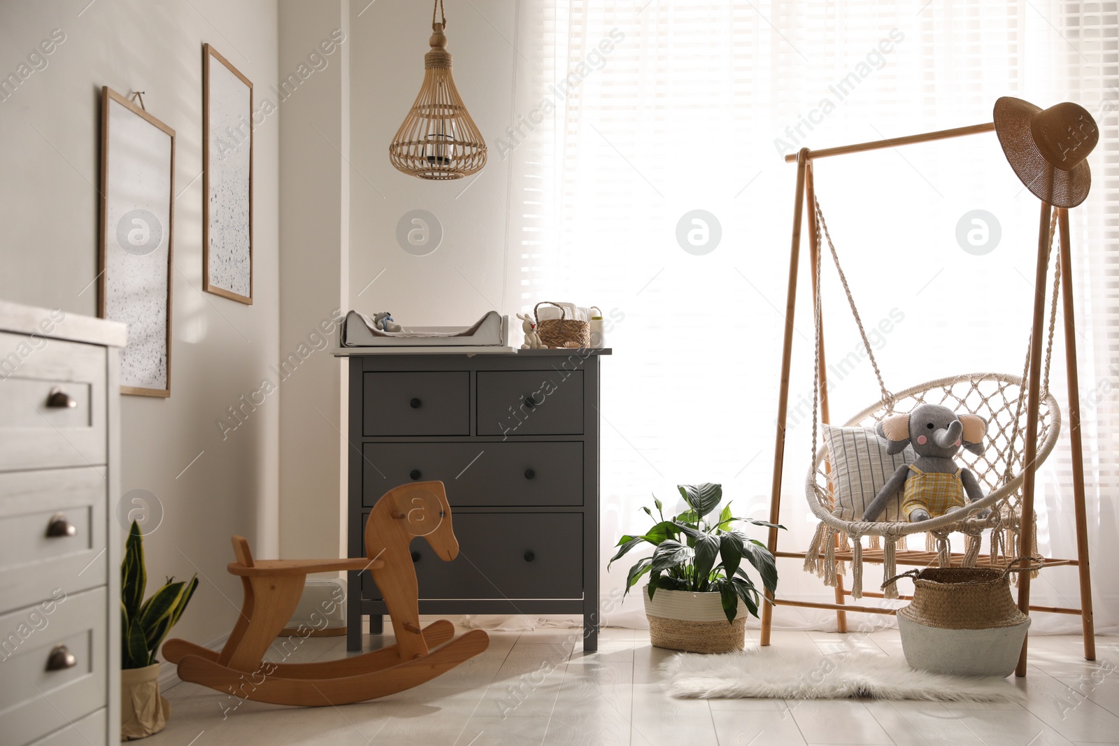 Photo of Baby room interior with modern changing table and wooden swing