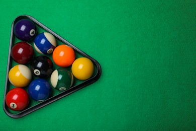 Photo of Plastic rack with billiard balls on green table, top view. Space for text