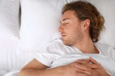 Photo of Handsome young man sleeping on pillow, top view with space for text. Bedtime