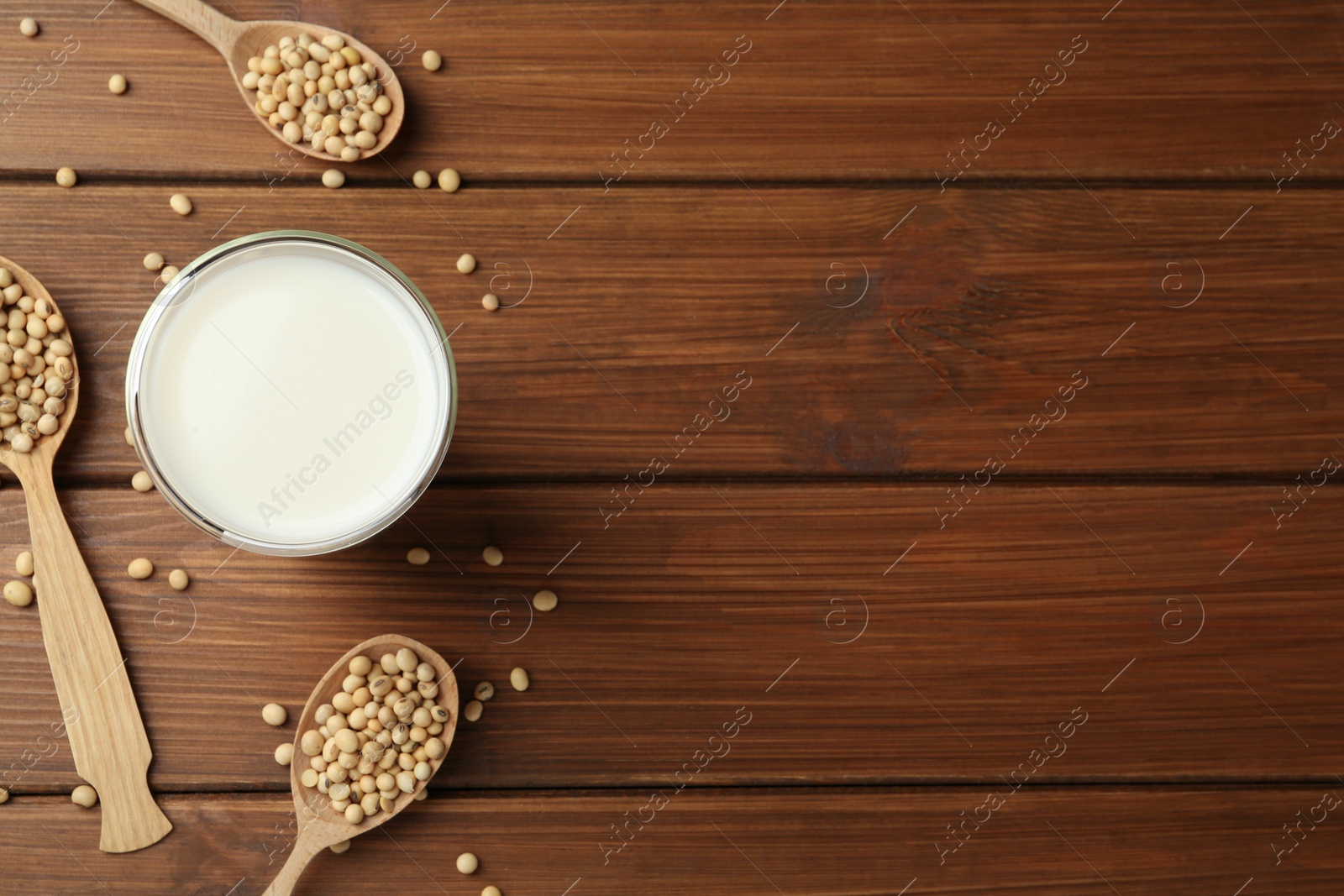 Photo of Fresh soy milk and beans on wooden table, flat lay. Space for text