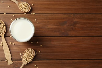 Photo of Fresh soy milk and beans on wooden table, flat lay. Space for text