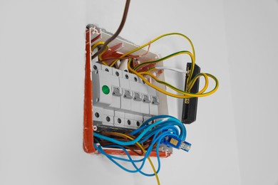 Photo of Switchboard with different cables on white wall. Installation of electrical wiring