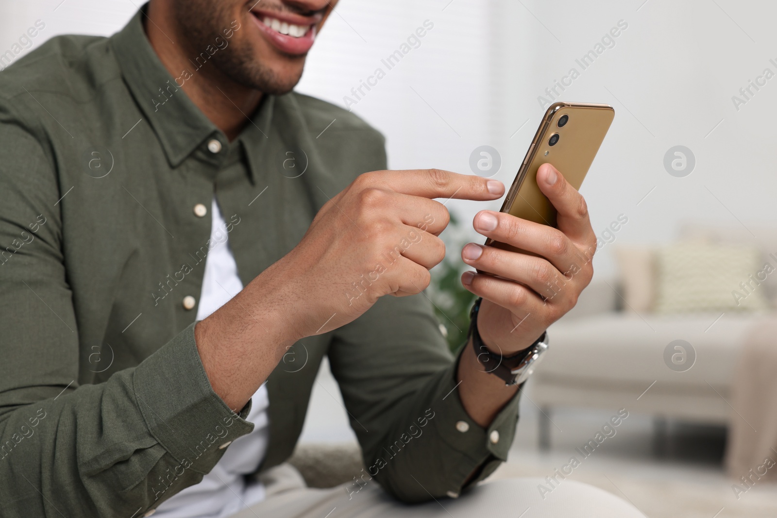 Photo of Man sending message via smartphone indoors, closeup