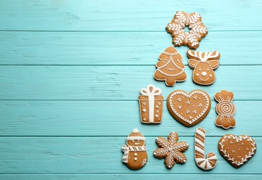 Photo of Christmas tree shape made of delicious gingerbread cookies on light blue wooden table, flat lay. Space for text