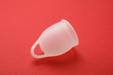 Photo of Menstrual cup on red background. Reusable female hygiene product