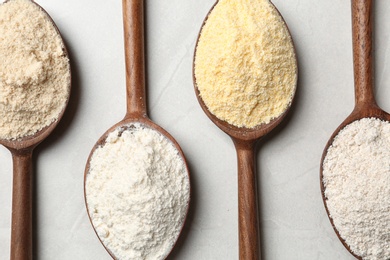 Photo of Spoons with different types of flour on table, top view