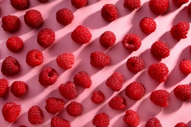 Photo of Tasty ripe raspberries on pink background, flat lay