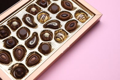 Box of delicious chocolate candies on pink background, closeup